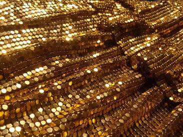 A piece of gold color metallic fabric is made of metal flakes.