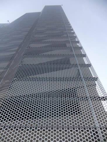 Silver white perforated sheet metal with hexagonal hole used as building facade.