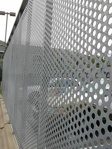Perforated sheet metal with round hole used in parking lot and beside the lot there are many cars.